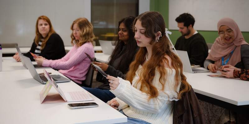 Students in the School for Business and Society in a seminar. The students are working in a small group and looking at printed materials.